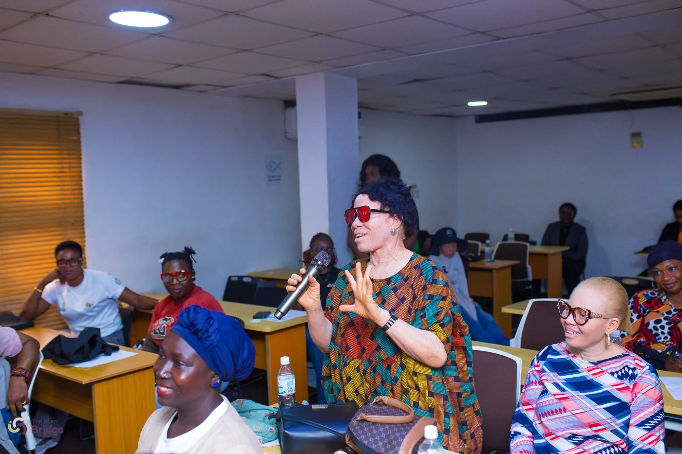 A community member speaks into a microphone, contributing to the Mum Bridge group dialogue