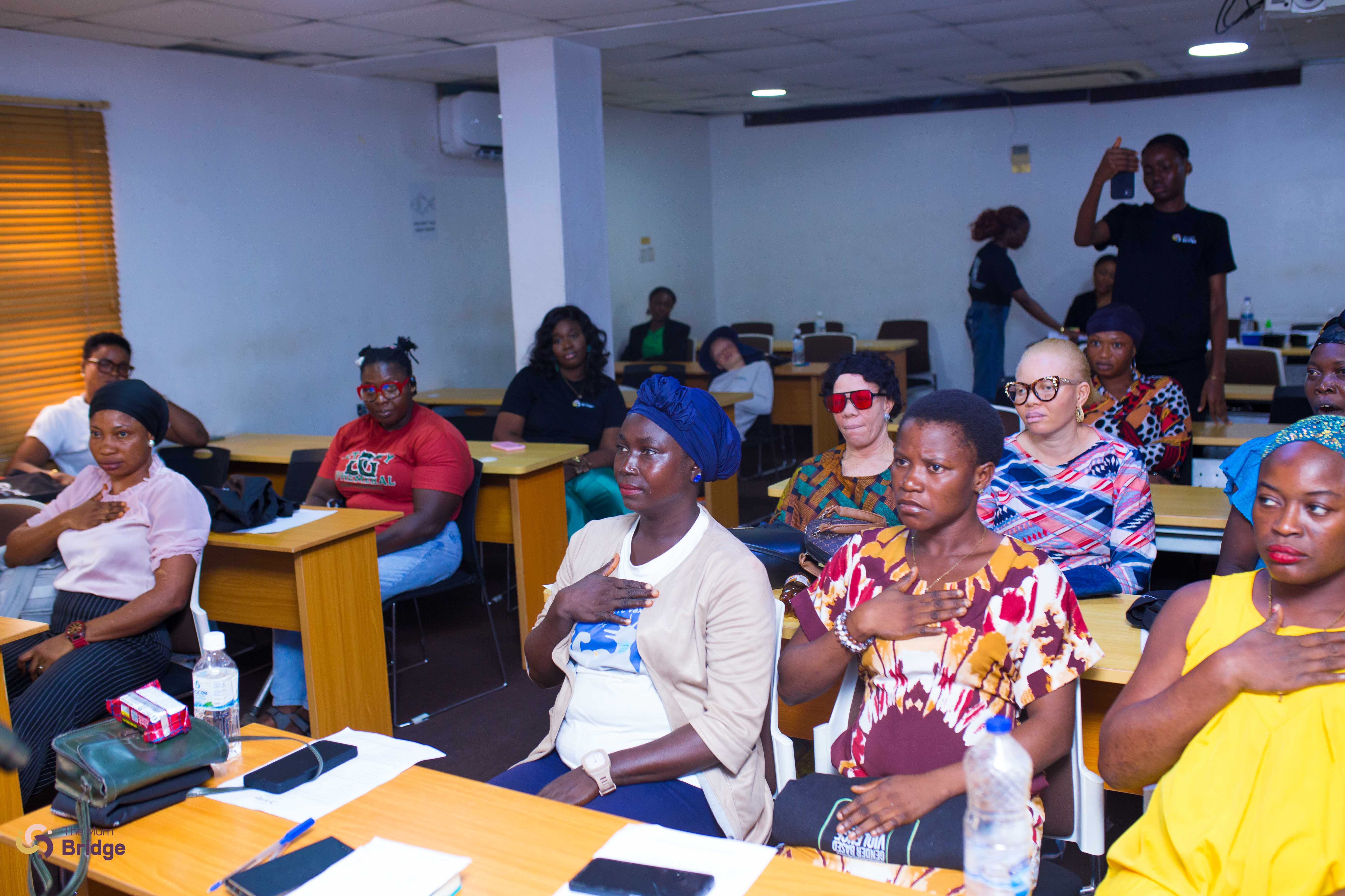 Mothers seated attentively with hands on their chests during a Mum Bridge programme