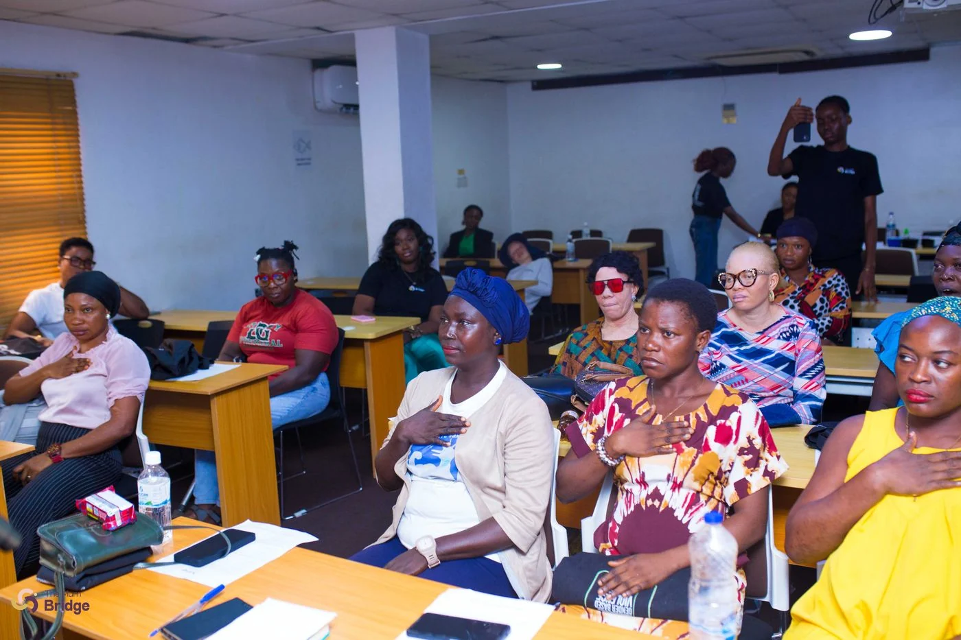 Mothers seated attentively with hands on their chests during a Mum Bridge programme