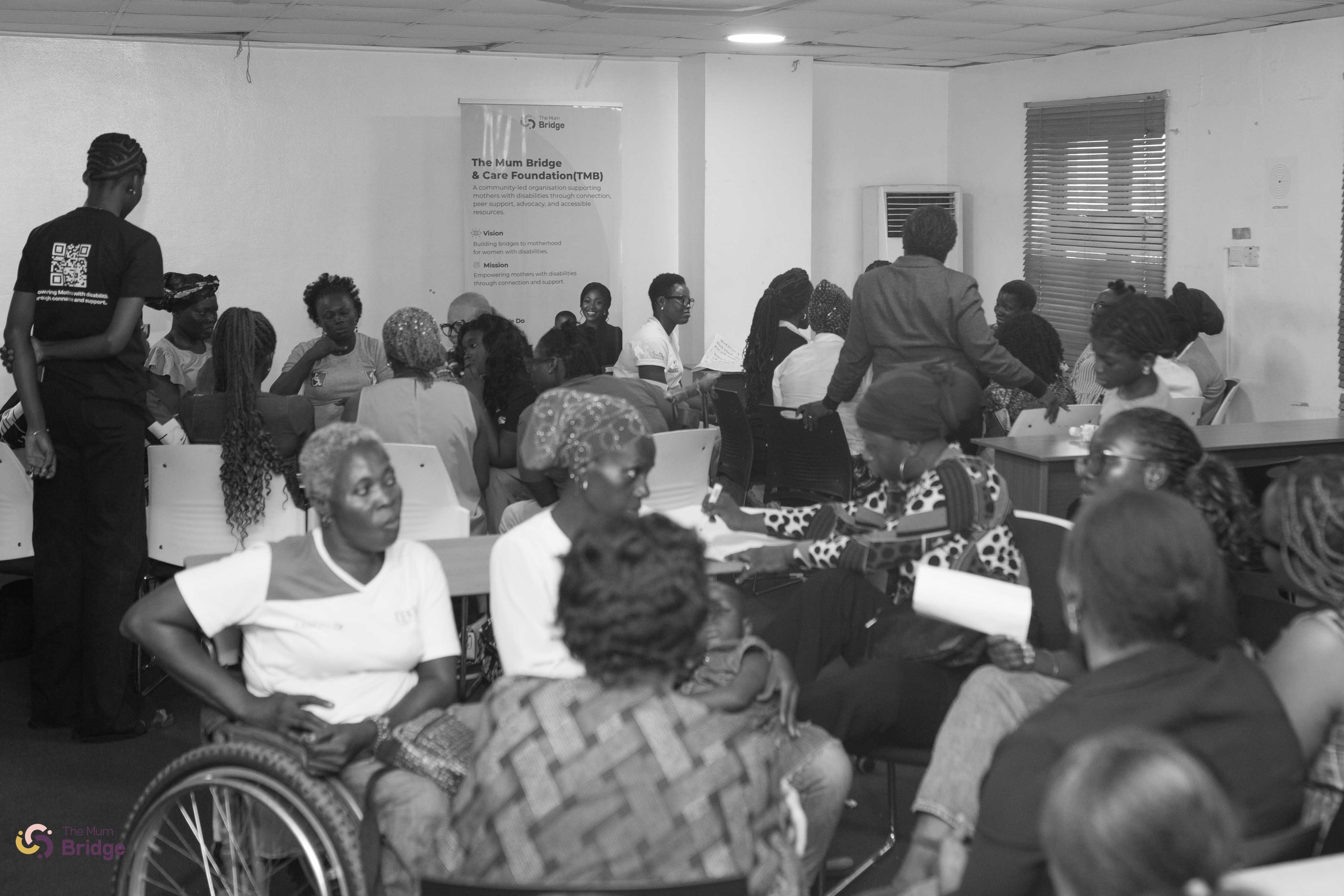 A wide view of The Mum Bridge community gathering, showing a full room of mothers including wheelchair users in attendance