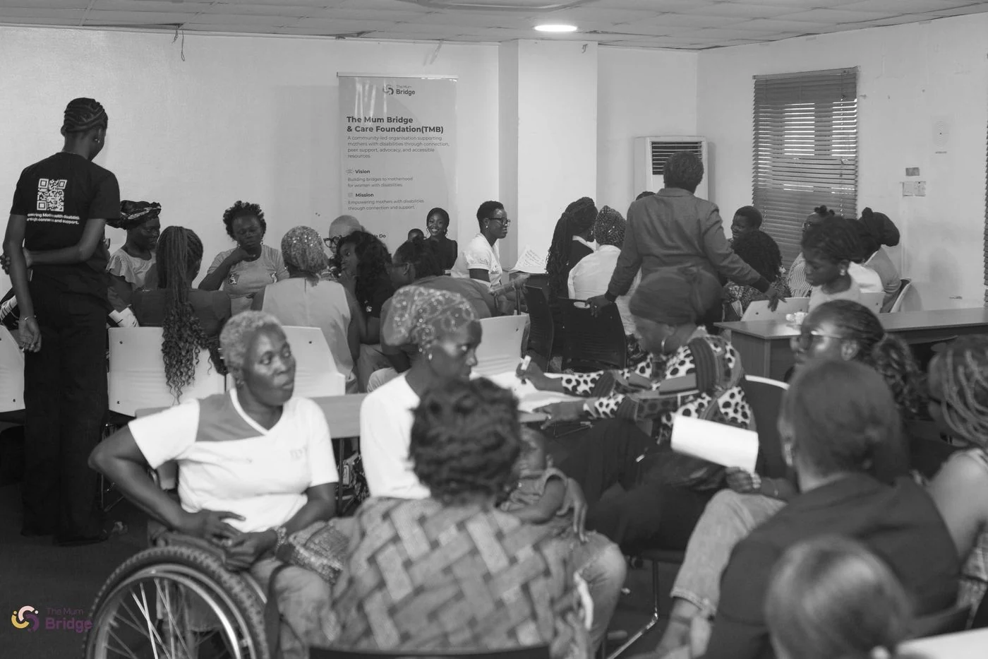 A wide view of The Mum Bridge community gathering, showing a full room of mothers including wheelchair users in attendance