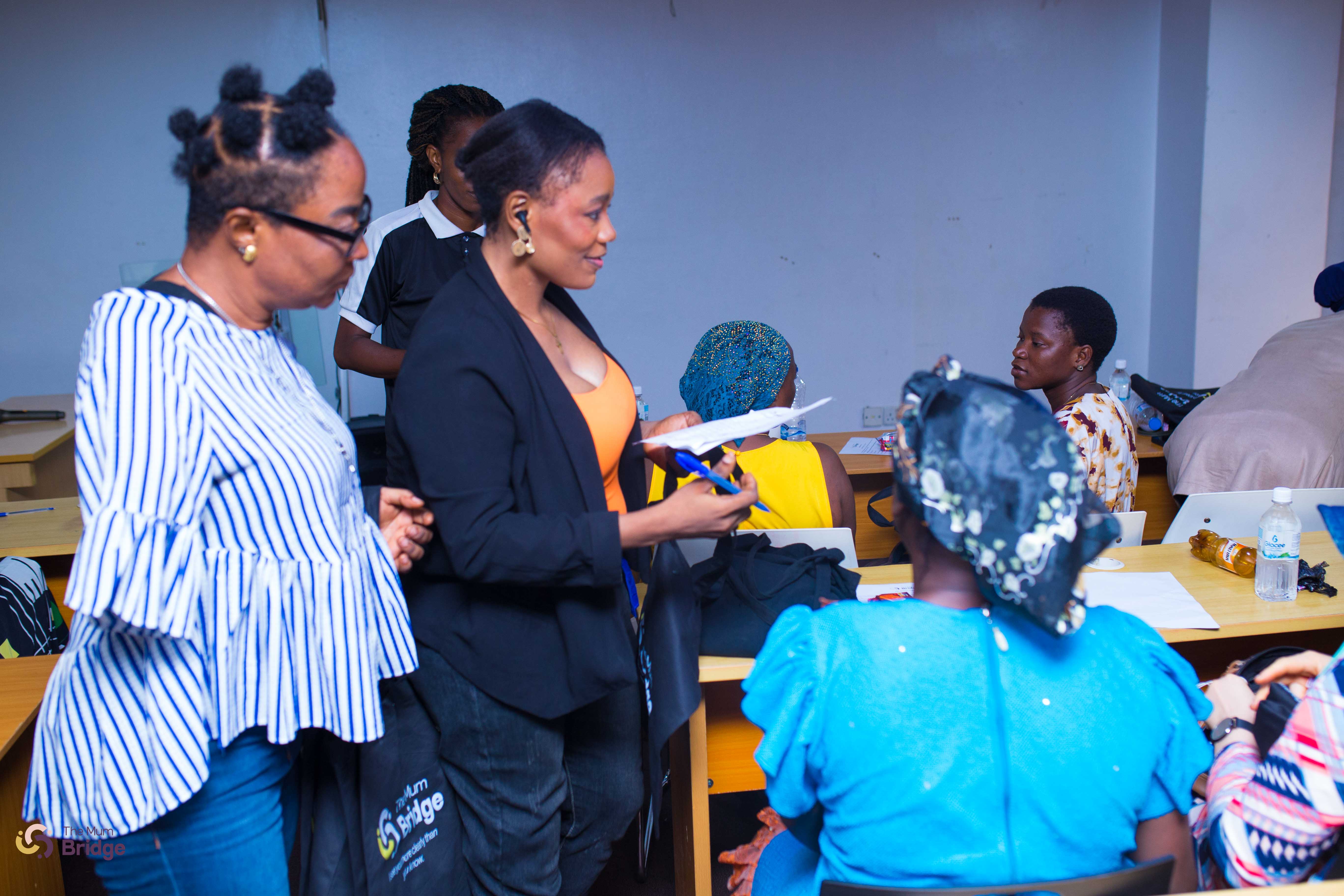 A Mum Bridge team member distributes materials to participants seated during the community programme