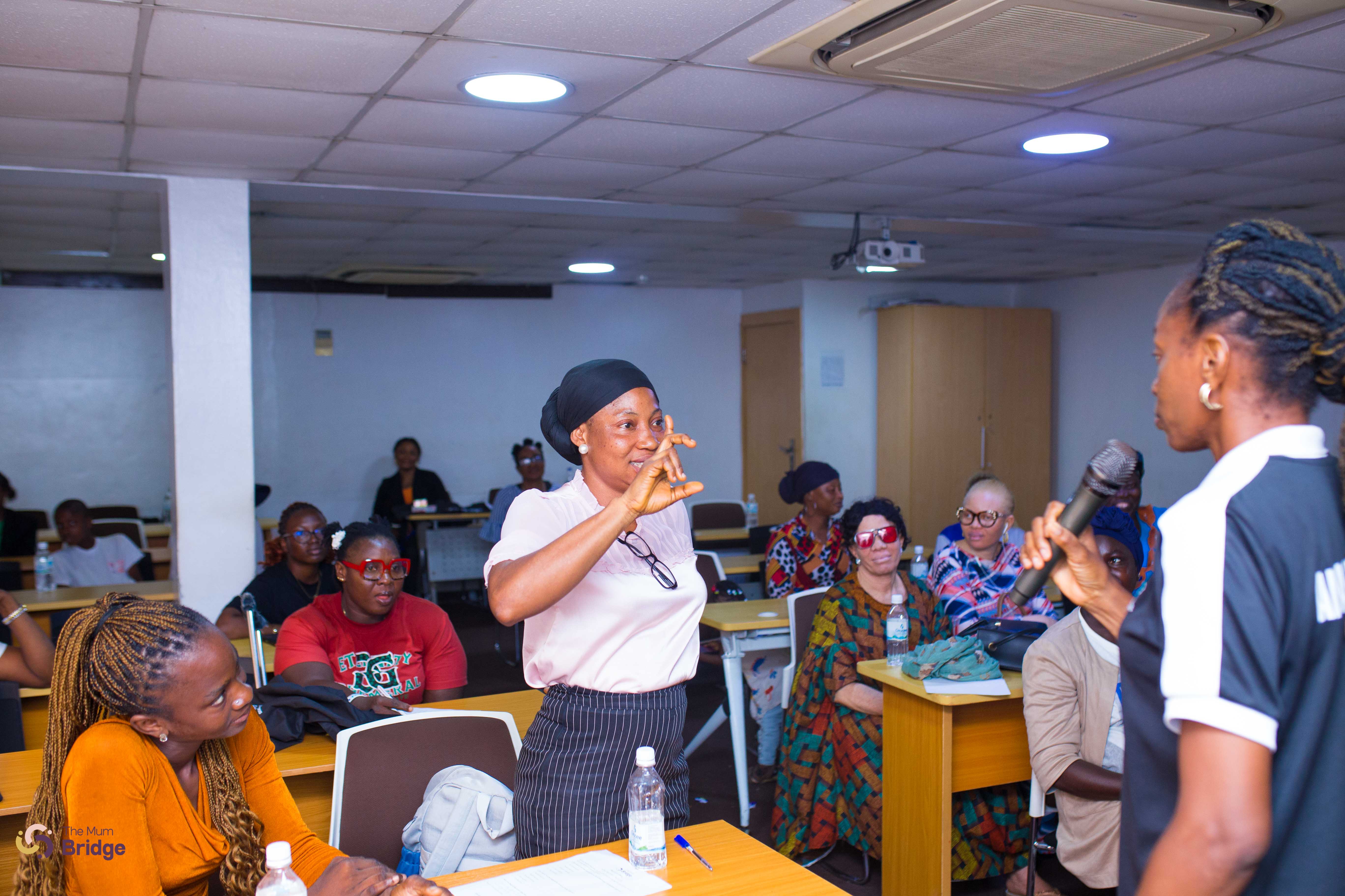 A community member stands to share her experience during an interactive Mum Bridge session, with the audience listening