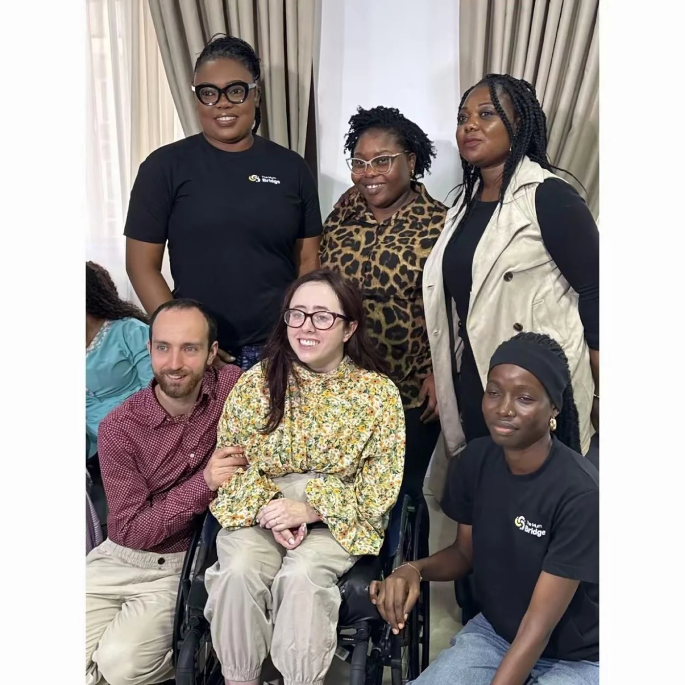 Group portrait from the Niamh Ni Hoireabhaird visit, with Mum Bridge team members standing behind seated wheelchair users